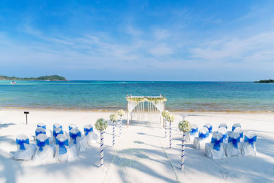 Deck chairs on beach against blue sky