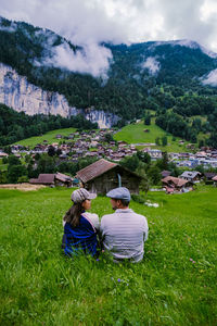 Rear view of people sitting on field against sky