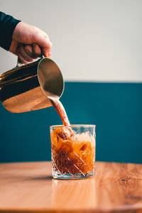 Close-up of hand pouring drink in glass on table