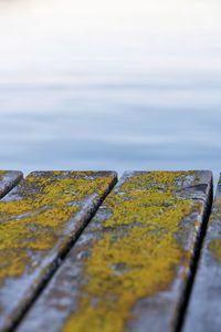 Close-up of yellow rusty metal by sea against sky