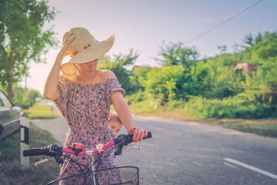 Son peeking from behind mother while sitting on bicycle