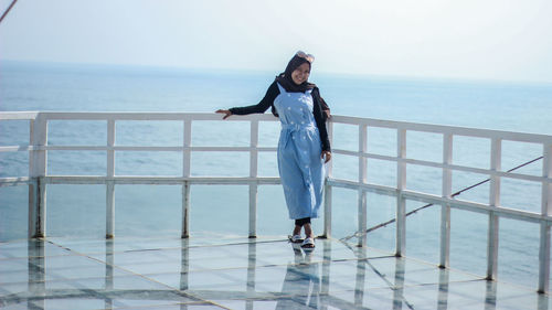 Woman standing on railing against sea
