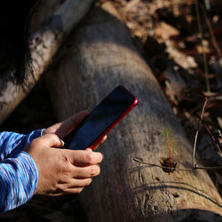 Cropped hands of man using mobile phone outdoors