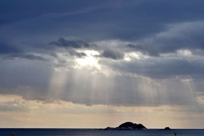 Sunlight streaming through clouds over sea