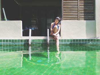 Mature woman resting while sitting by swimming pool