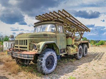 View of truck on field against cloudy sky