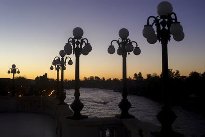 Silhouette trees by lake against clear sky during sunset