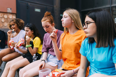 Girls sitting together eating snacks