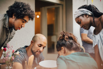 Curious multi-ethnic male and female friends looking down during dinner party