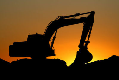 Silhouette of excavator against sky during sunset