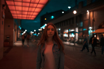 Portrait of woman standing against illuminated building