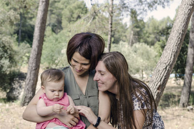 Happy mother and daughter on tree against blurred background