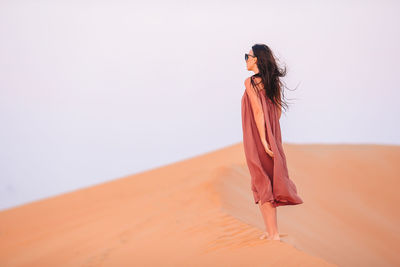 Side view of young woman standing against white background