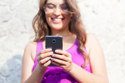 Smiling woman using mobile phone in sunny day