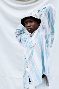 Portrait of young man standing against white wall