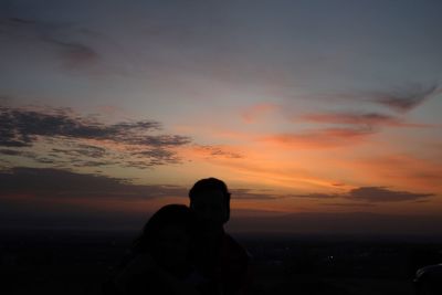 Silhouette woman standing against sky during sunset