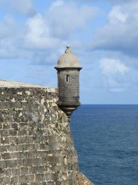 Lighthouse by sea against sky