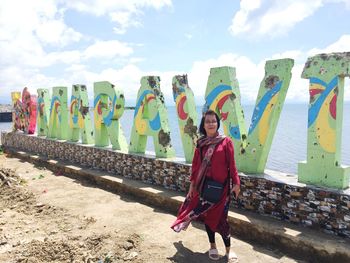 Portrait of woman standing against text at beach