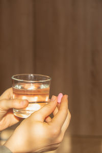 Cropped hands of woman holding drink on table