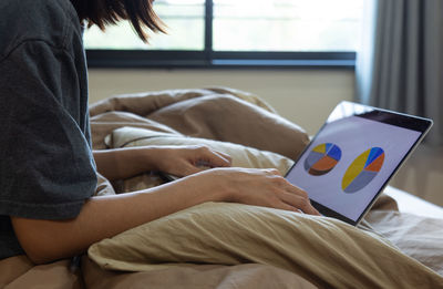 Midsection of man sitting on bed at home