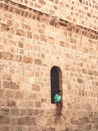 Man with umbrella standing against brick wall