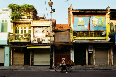 Woman riding bicycle on street against building