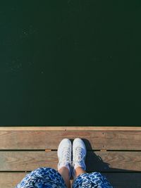 Low section of man standing on pier over lake