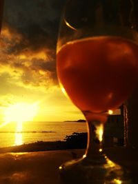 Close-up of beer at beach during sunset