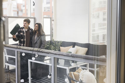 Multiracial couple looking through window while exploring new house