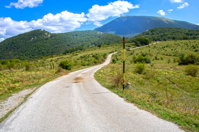 Road leading towards mountains against sky