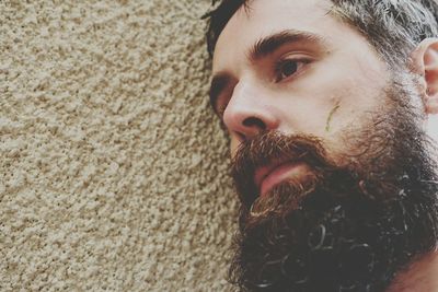 Close-up of bearded tensed man leaning on wall