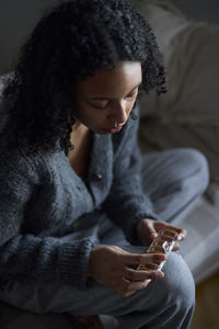 Pensive young woman holding pill box