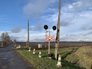 Road sign on field against sky