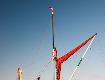 Low angle view of flag hanging on mast against clear blue sky