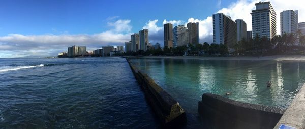 City at waterfront against cloudy sky