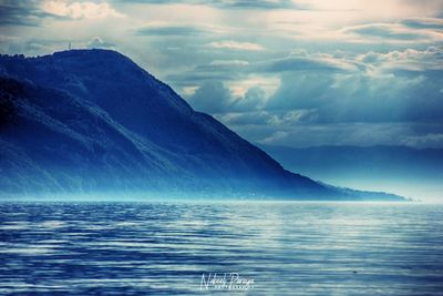 Scenic view of sea and mountains against sky