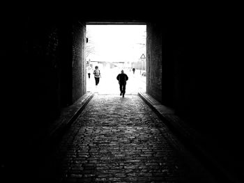 Rear view of woman walking in tunnel