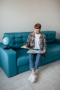 Full length of man sitting on sofa at home