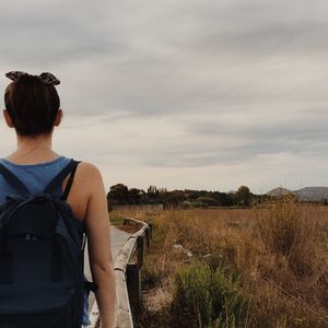 Rear view of woman against cloudy sky