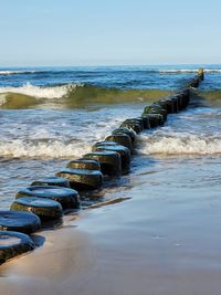 Wooden posts in sea against sky