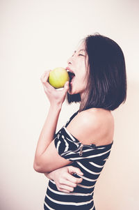 Midsection of woman holding apple against white background