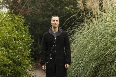 Portrait of young man standing against plants