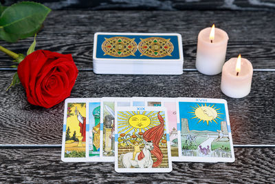 High angle view of tarot cards with candles and rose on table