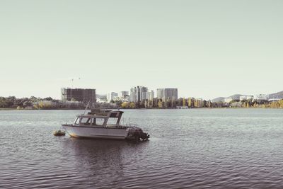 Boats in river with city in background