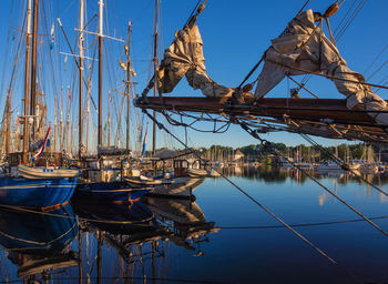 Sailboats moored at harbor against sky