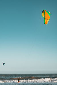 Man kiteboarding on sea against clear sky