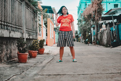 Full length portrait of young woman standing in city