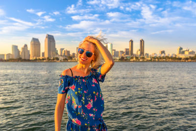Smiling woman wearing sunglasses while standing in city