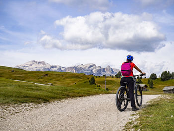 Man riding bicycle on field against sky