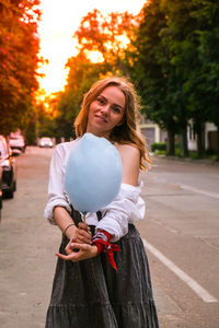 Portrait of smiling young woman standing on street in city